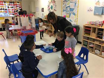 Children measuring water at small group