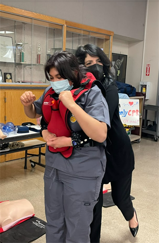 Elodia practicing heimlich maneuver on high school student